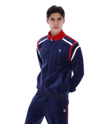 Man wearing a navy tracksuit with red and white accents, with a FILA logo on the chest, paired with matching bottoms, against a white background