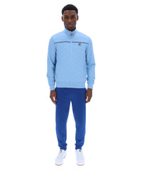 Man wearing a light blue tracksuit with a logo on a white background
