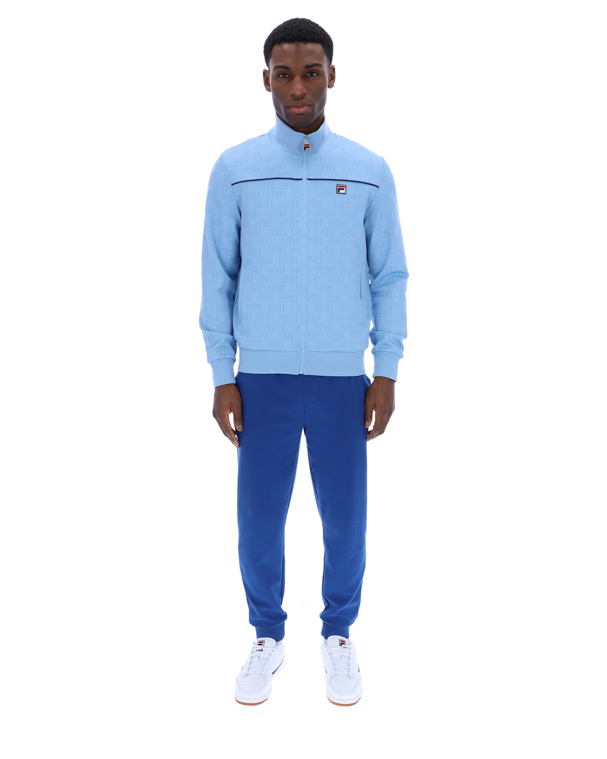 Man wearing a light blue tracksuit with a logo on a white background