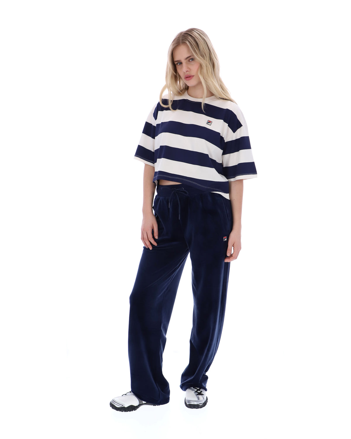Woman wearing a striped shirt and navy pants on a white background