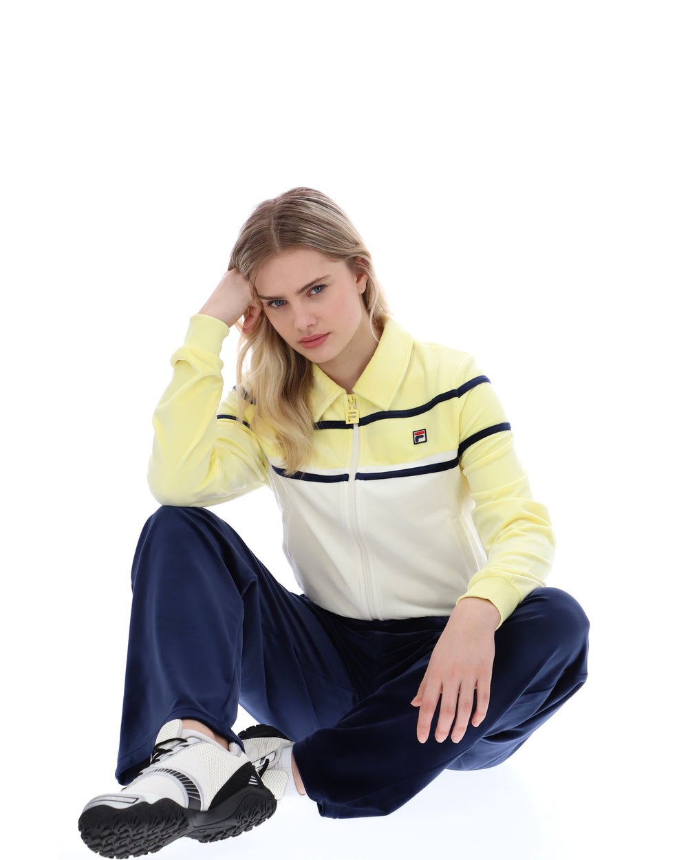 Woman wearing a yellow and white striped hoodie with navy pants on a white background