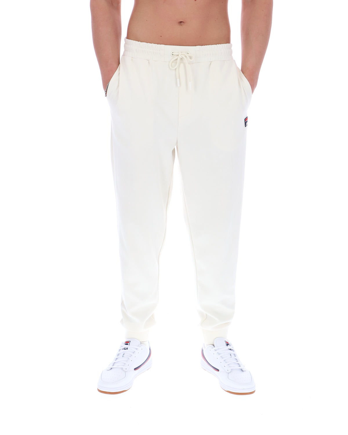White sweatpants with a FILA logo worn by a person on a white background