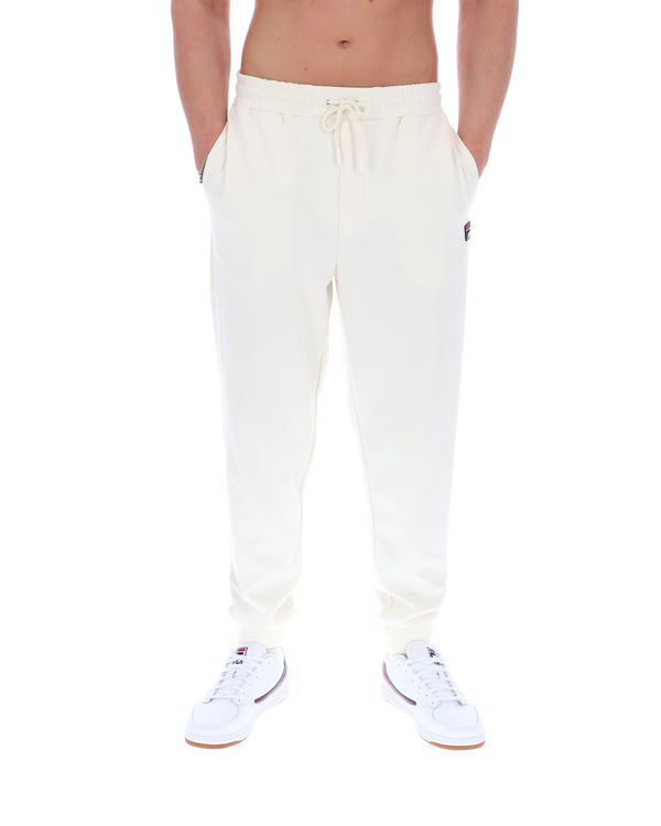 White sweatpants with a FILA logo worn by a person on a white background