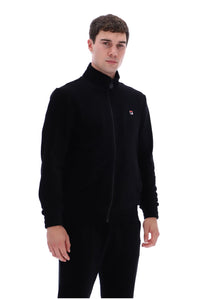 A man wearing a black zip-up fleece jacket with a small red, white, and blue Filson logo on the left chest, paired with black pants, against a plain white background.