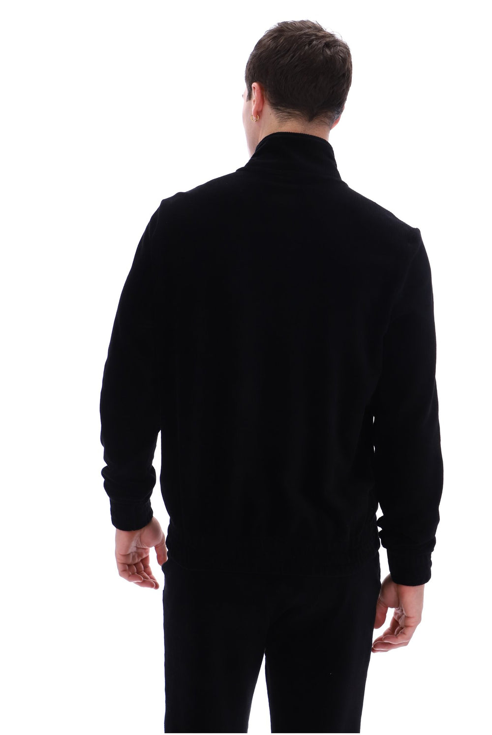 A man viewed from behind wearing a black long-sleeve mock neck sweater and black pants against a plain white background.