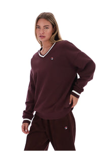 A woman modeling a matching burgundy sweatshirt and sweatpants set with white trim and small Fila logos, shot against a plain white background.