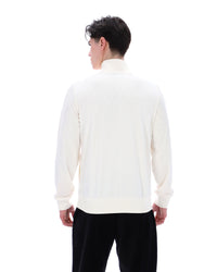 Person wearing a white sweater and black pants on a white background