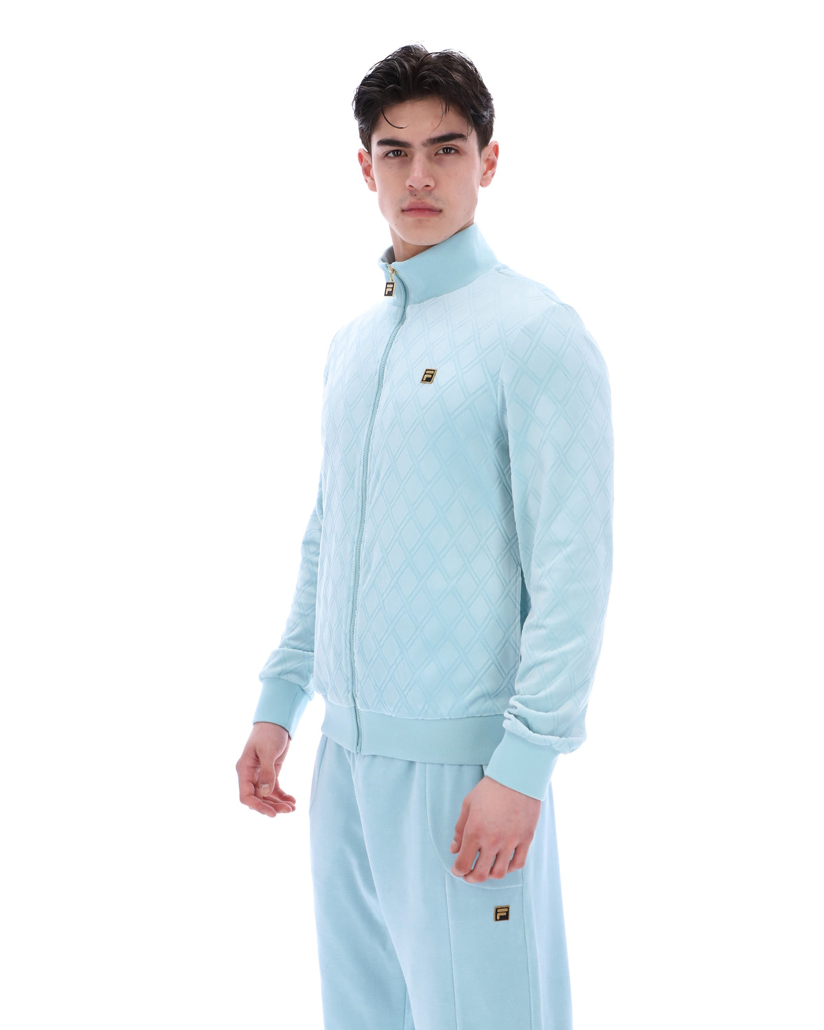 Man wearing a light blue tracksuit with a brand logo on a white background