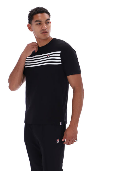 A man wearing a black short-sleeve t-shirt with a horizontal white stripe pattern across the chest and matching black sweatpants, featuring the Fila logo on the chest and thigh.