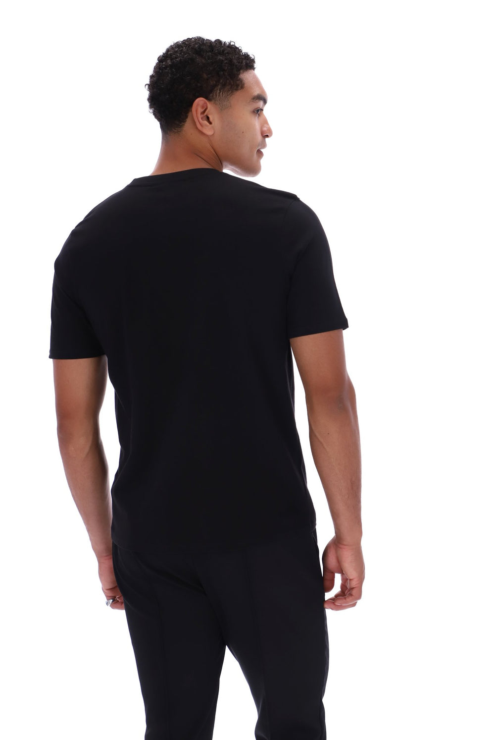 A man wearing a plain black short-sleeve t-shirt and black pants, photographed from the back against a solid white background.