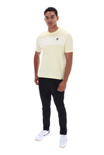 A man modeling a pale yellow short-sleeve t-shirt with three horizontal white stripes across the chest and a small red and white logo on the left chest, paired with black pants and white sneakers, against a plain white background.
