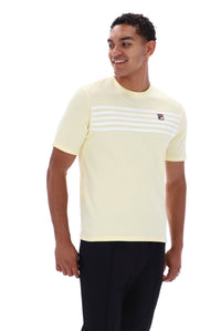 A man wearing a pale yellow short-sleeve t-shirt with white horizontal stripes across the chest and a small Fila logo, paired with black pants, against a plain white background.