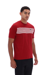 A man wearing a red short-sleeve athletic t-shirt with horizontal white stripes across the chest and a small logo on the right chest, paired with black pants, against a plain white background.