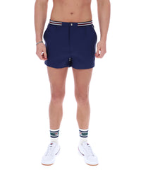 Person wearing navy shorts with white sneakers and socks on a white background