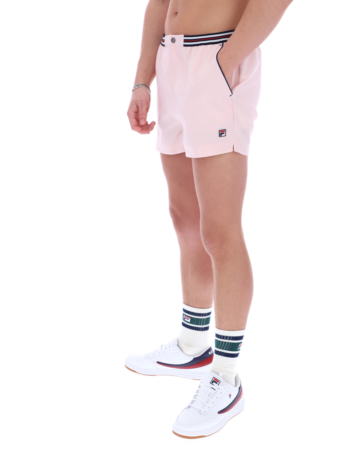 Person wearing light pink shorts with a FILA logo on a white background