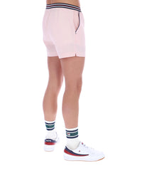 Person wearing light pink shorts, white sneakers with red and blue accents, and striped socks on a white background.