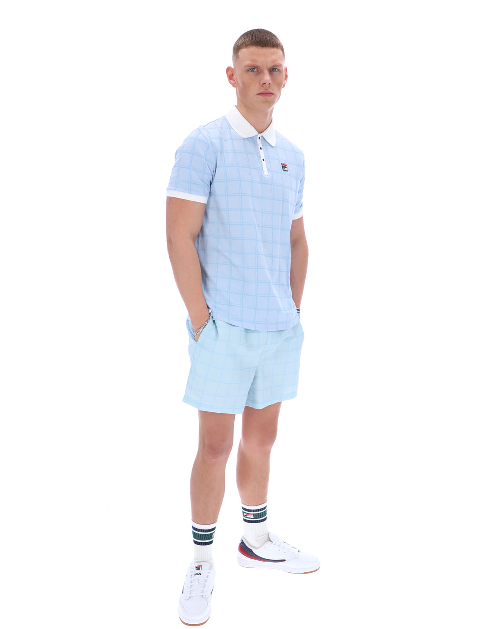 Man wearing a light blue striped polo shirt and shorts set on a white background
