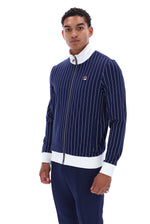 A man modeling a navy blue pinstriped zip-up jacket with white trim and a small red, white, and blue Filson logo on the chest, paired with navy pants, against a plain white background.