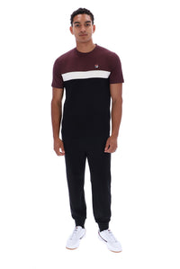A man modeling a short-sleeve t-shirt and matching jogger pants set. The t-shirt features a maroon upper chest, a white horizontal stripe across the chest, and a solid black lower body.