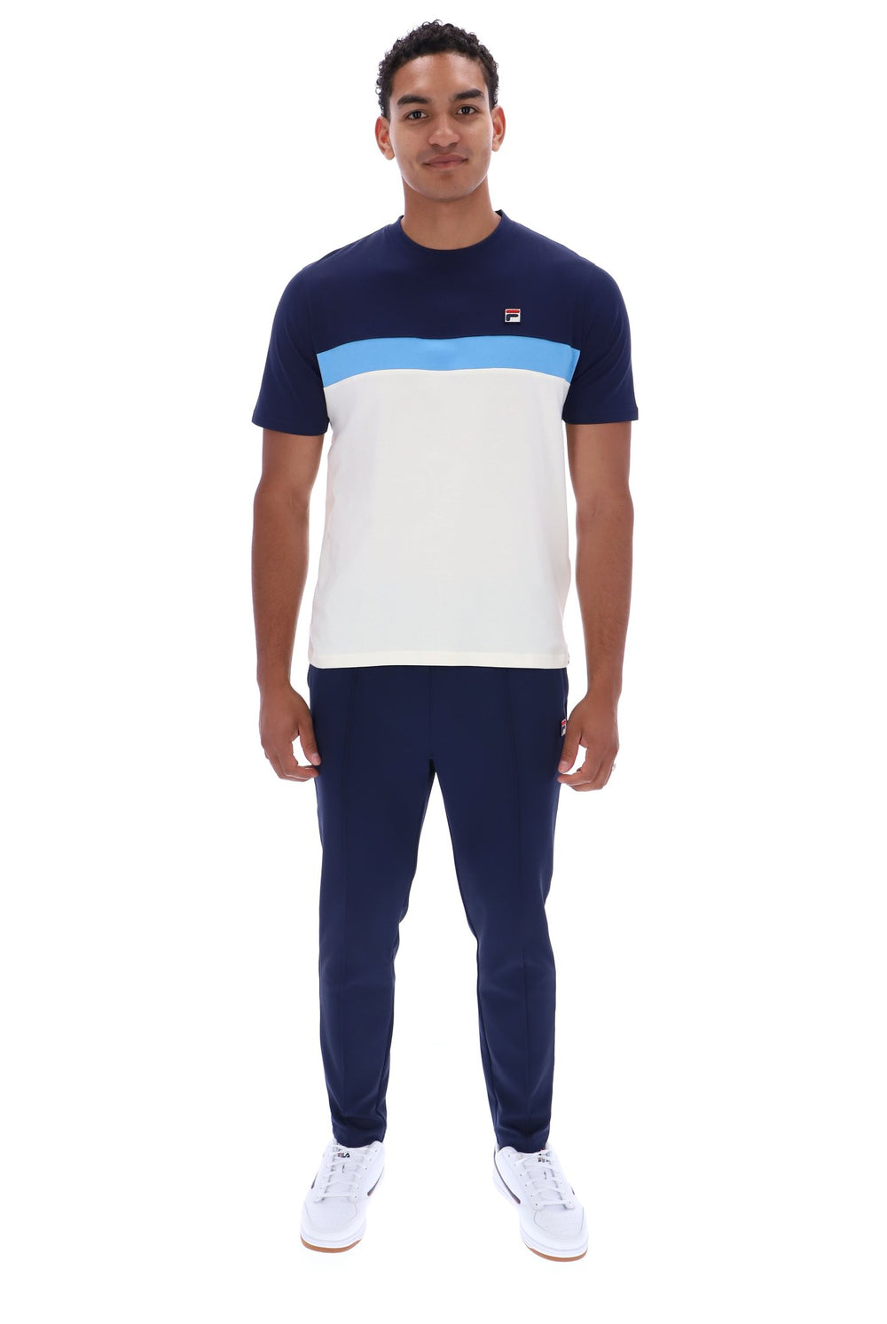 A man modeling a short-sleeve colorblock t-shirt and matching navy pants. The t-shirt features a navy blue upper section, a light blue horizontal stripe across the chest, and a large white block on the lower half.