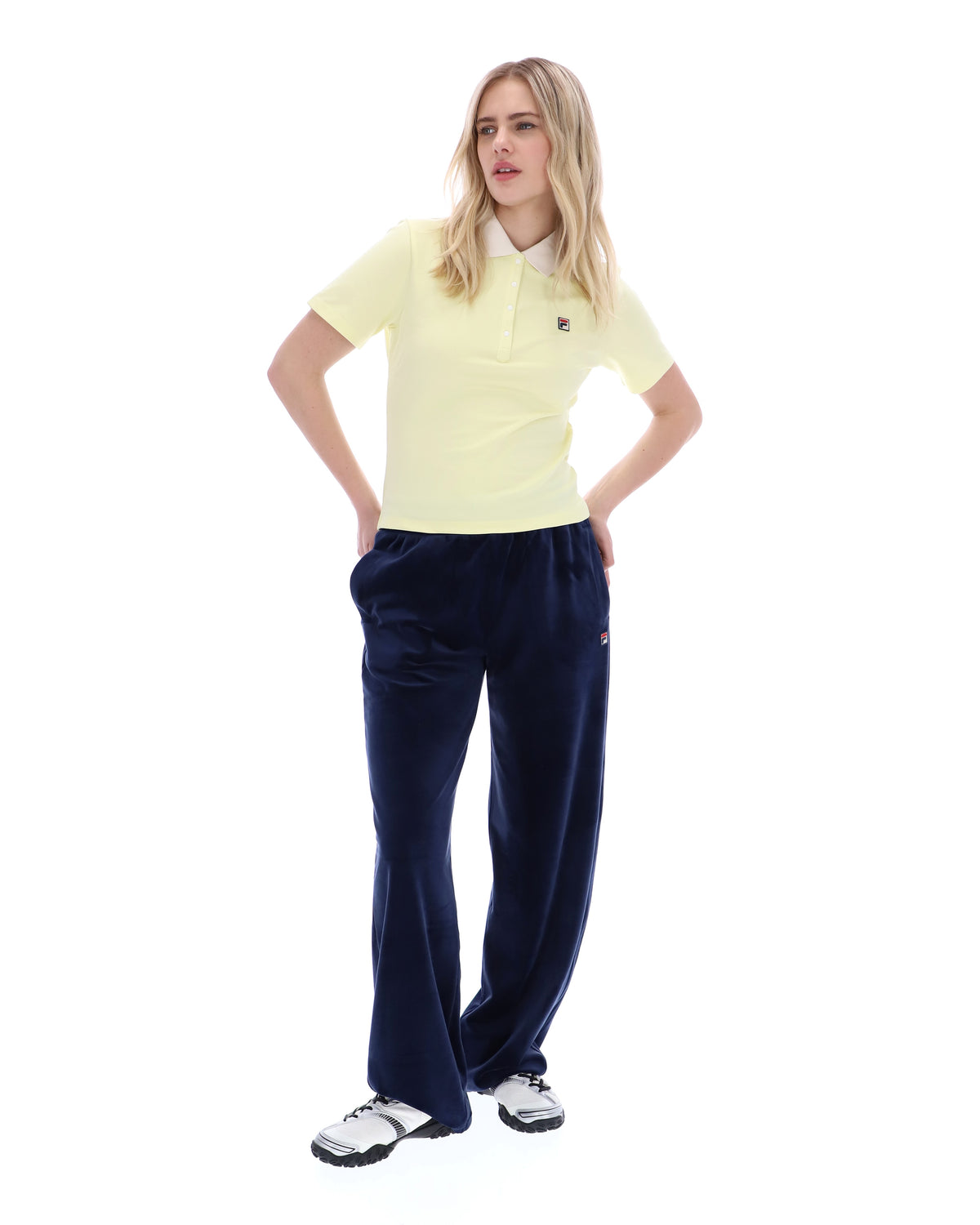 Woman wearing a yellow polo shirt and navy pants on a white background