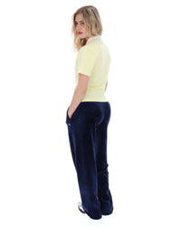 Woman wearing a yellow polo shirt and navy blue pants on a white background