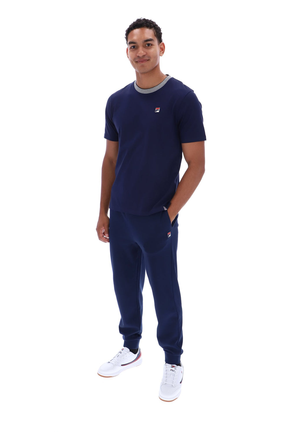 A man modeling a navy blue Filippa Deoxy crewneck t-shirt and matching jogger sweatpants set, featuring a small red and white logo on the chest, against a plain white background.