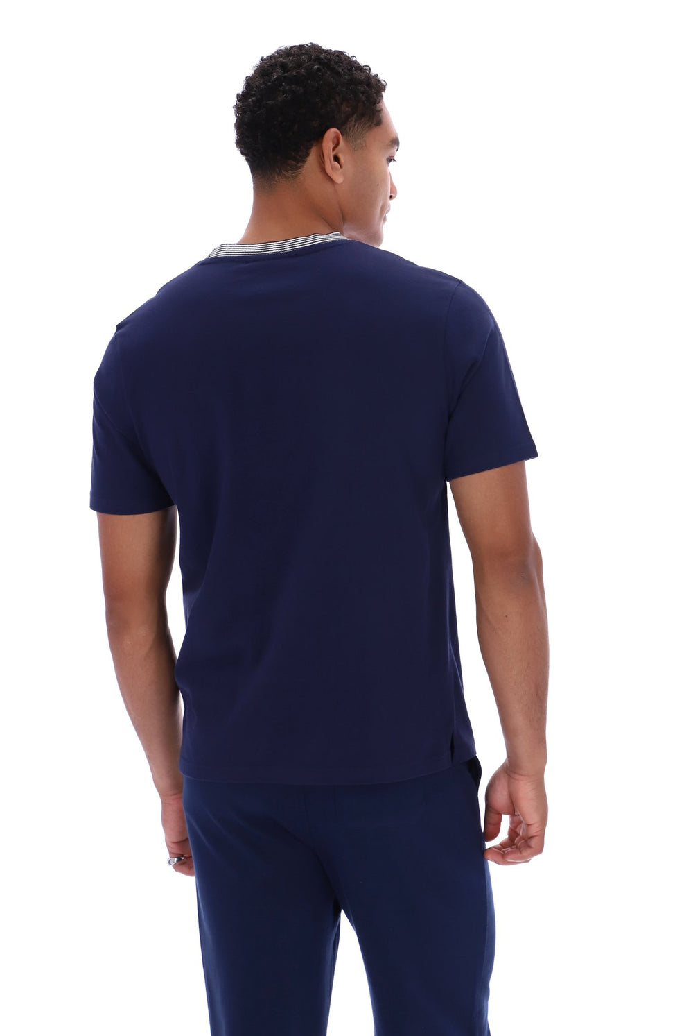 A man viewed from the back wearing a navy blue short-sleeve t-shirt with a light gray crew neck trim and matching navy pants, against a plain white background.