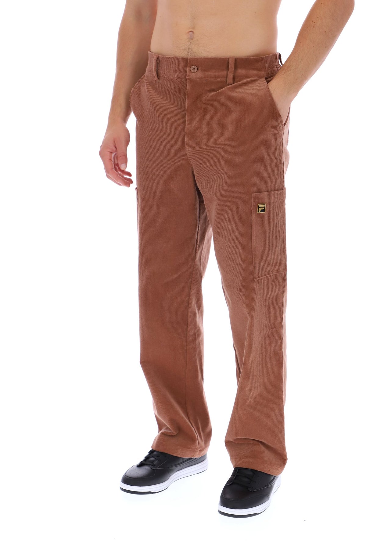 A person modeling a pair of brown corduroy cargo pants with black sneakers, shown from the waist down against a plain white background.