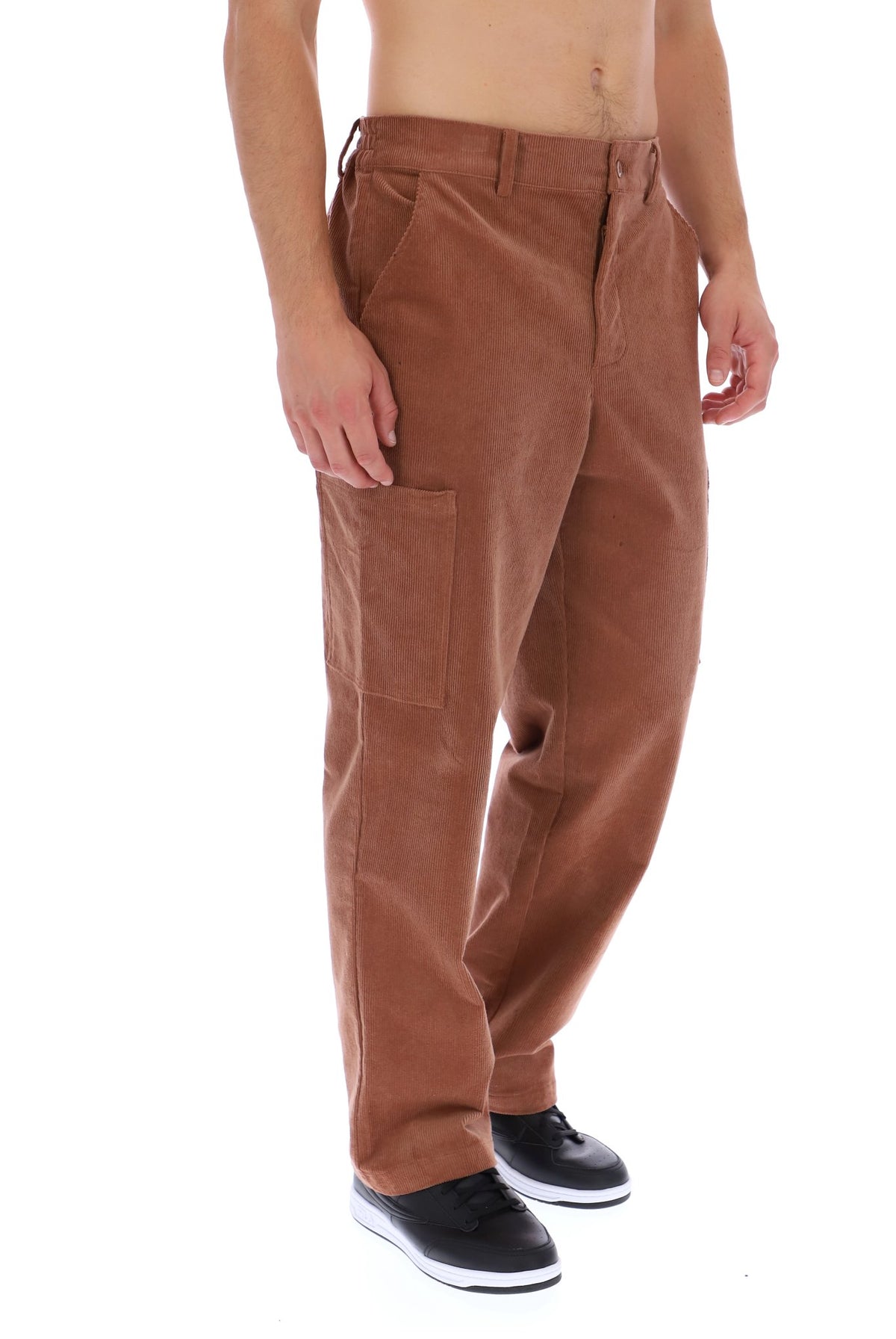 A person modeling a pair of brown corduroy cargo pants with black sneakers, shown from the waist down on a white background.