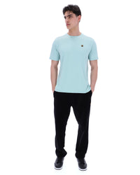 Man wearing a light blue t-shirt and black pants on a white background