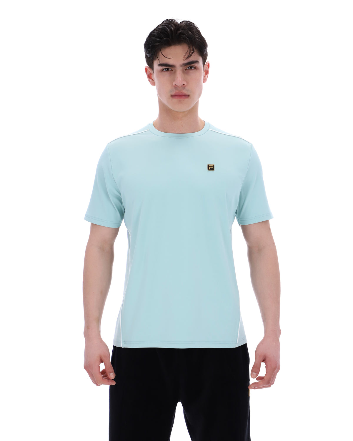 Man wearing a light blue t-shirt with a small logo on a white background