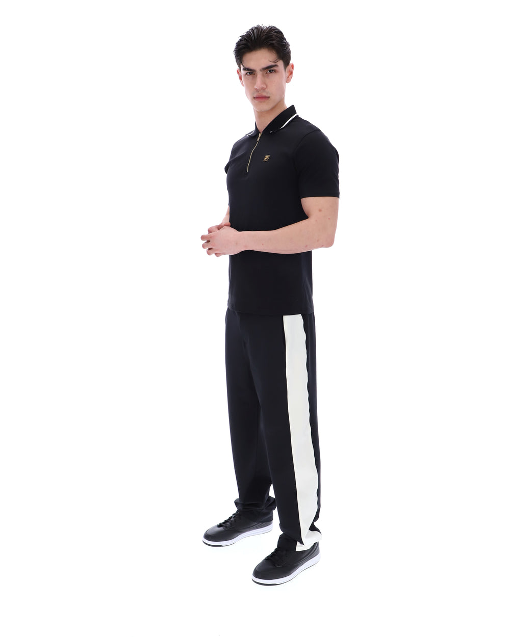 Man wearing a black polo shirt with a small logo on a white background