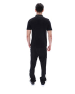 Man wearing a black polo shirt with a small logo on a white background