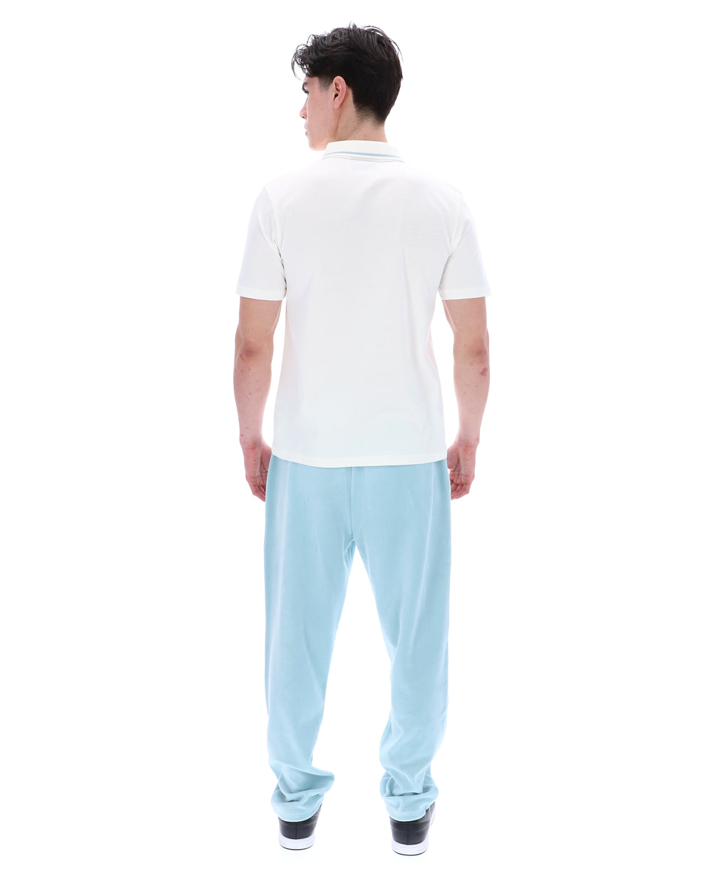 Person wearing a white polo shirt and light blue pants on a white background