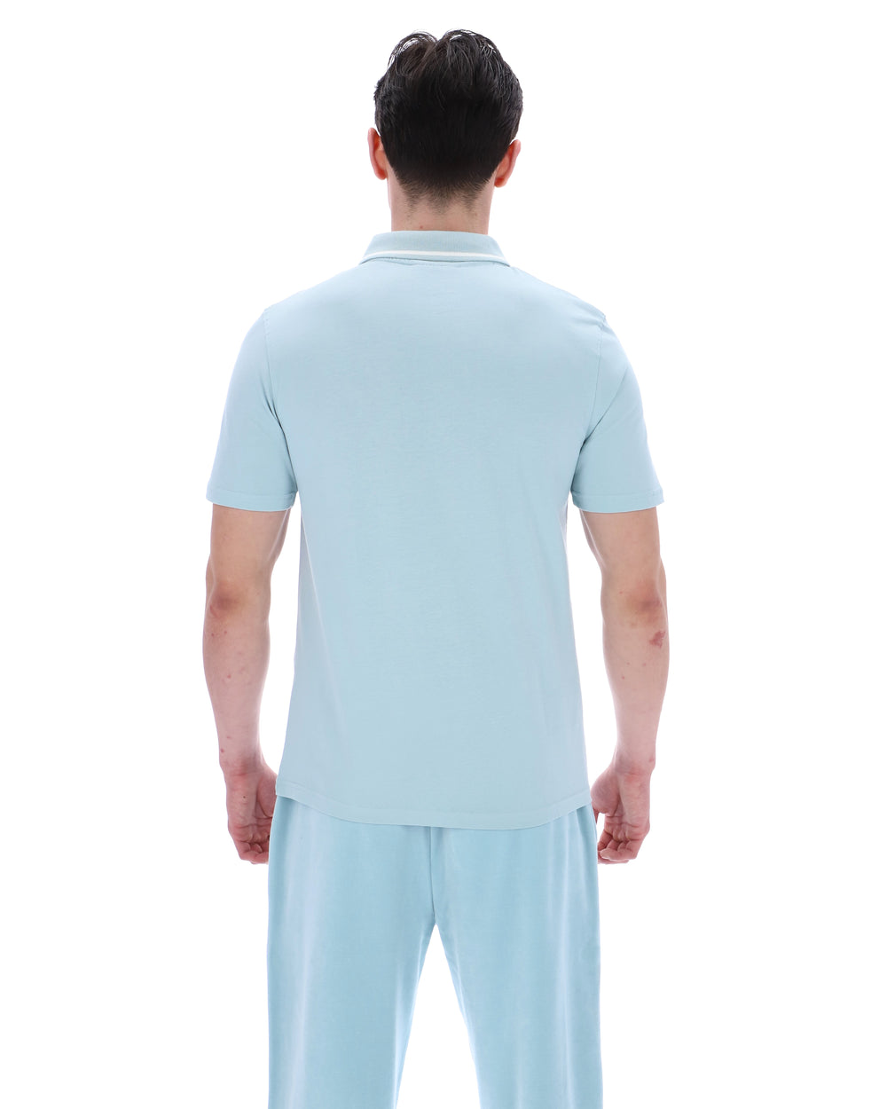 A man wearing a light blue polo shirt with matching bottoms, on a white background