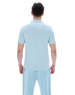 A man wearing a light blue polo shirt with matching bottoms, on a white background