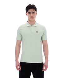 Man wearing a light green polo shirt with a small logo on a white background