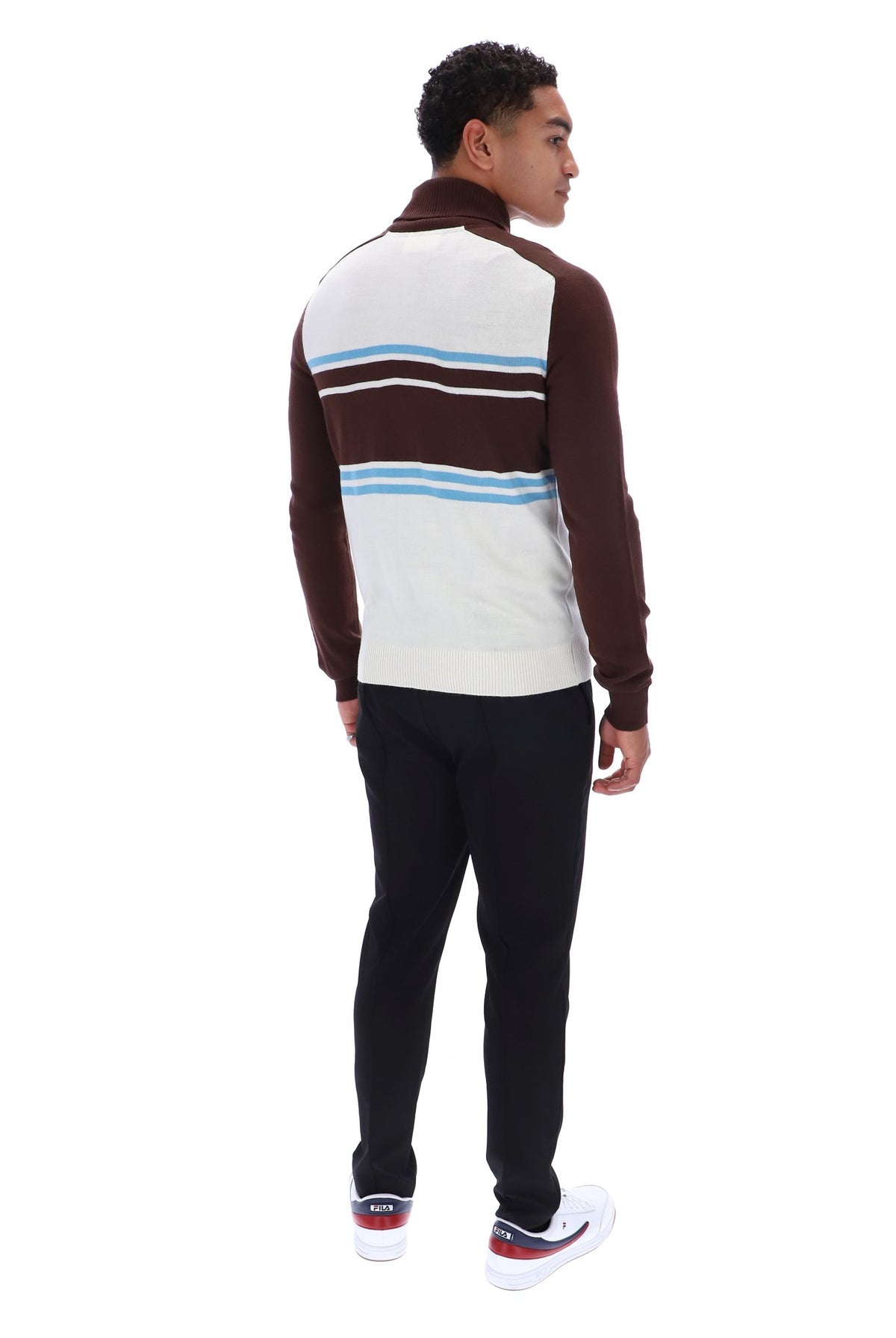 A man shown from the back wearing a brown and white striped quarter-zip pullover sweater with light blue accents, paired with black pants and white sneakers, on a solid white background.