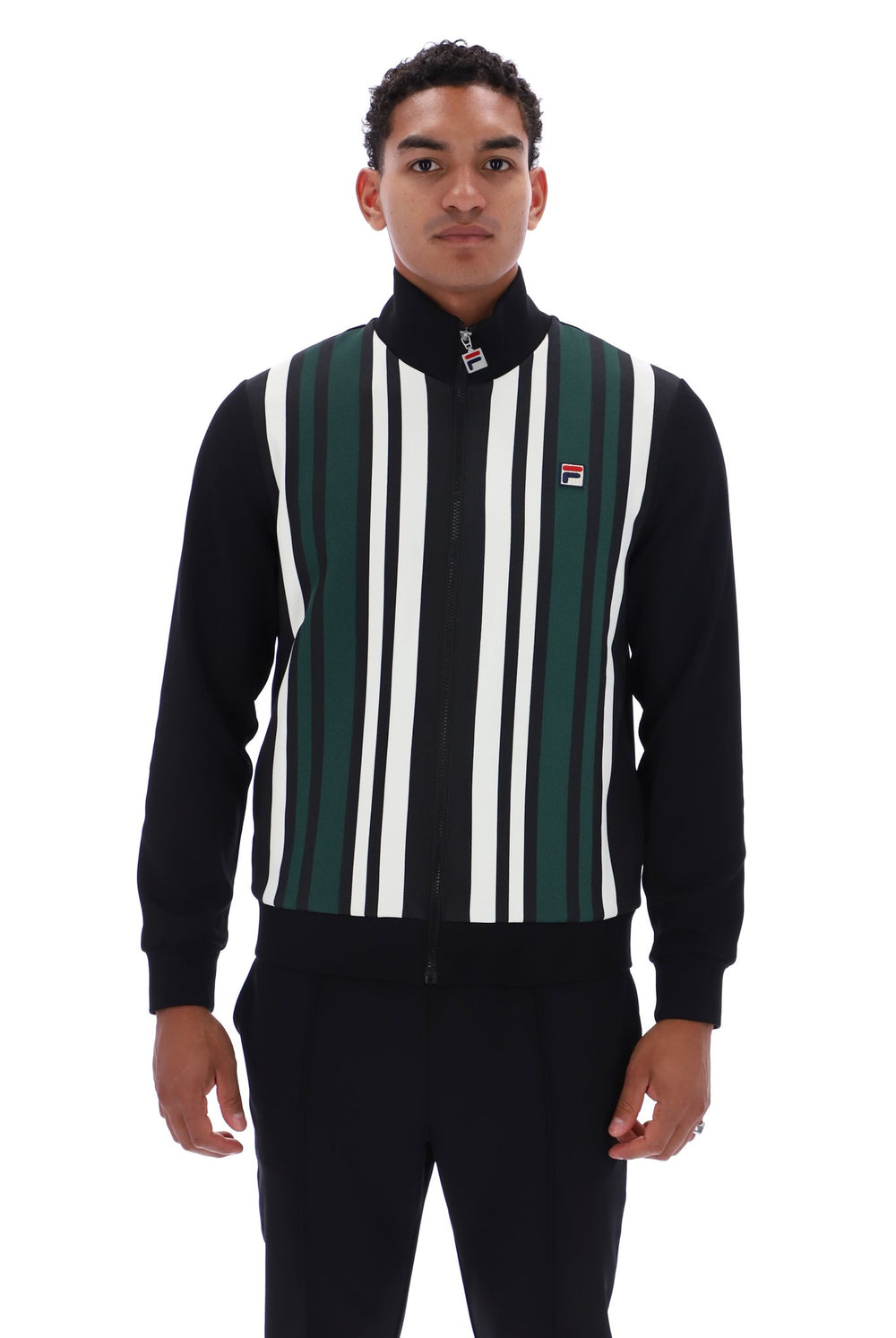 A man wearing a black zip-up track jacket with vertical green, white, and black stripes on the front, featuring a small Fila logo on the chest, set against a plain white background.