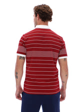 A man viewed from the back wearing a red short-sleeve polo shirt with thin white horizontal stripes and a white collar, paired with navy pants, against a plain white background.