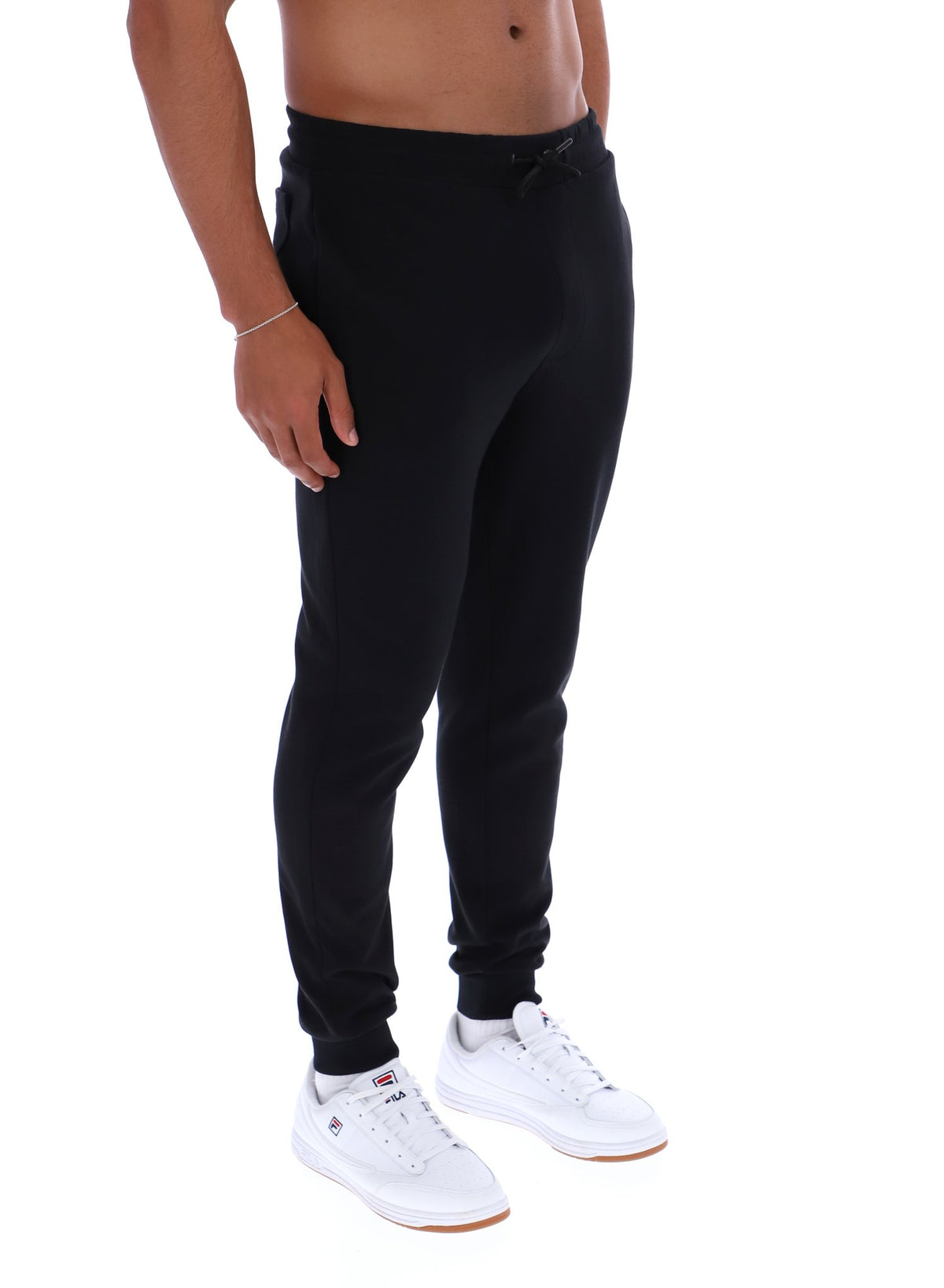 Person wearing black jogger pants and white sneakers on a white background