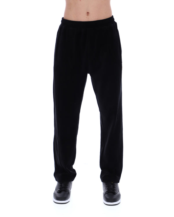 Displays the model wearing the Black 'FILA' branded Lorrie Velour Track Pant