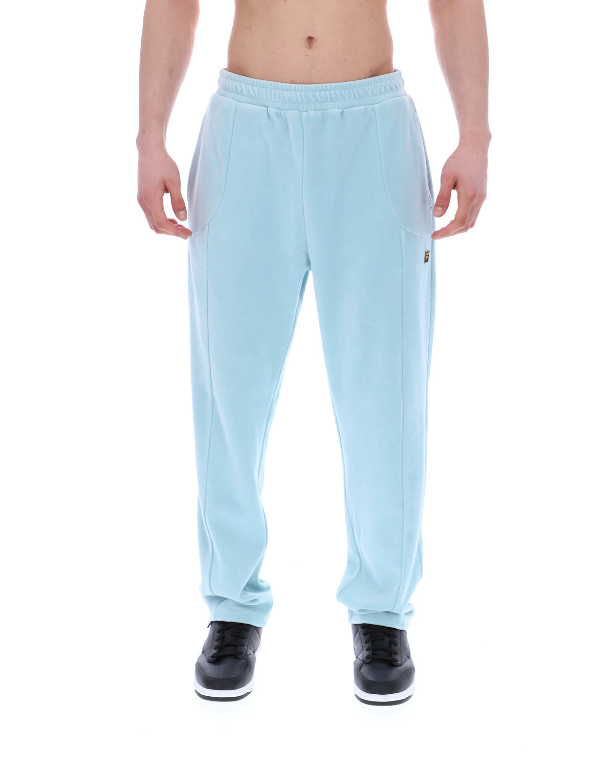 Light blue velour sweatpants with a small FILA logo, worn by a person against a white background
