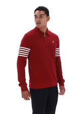 A man wearing a red quarter-zip pullover sweater with white stripes on the sleeves and a small logo on the chest, paired with black pants, against a plain white background.