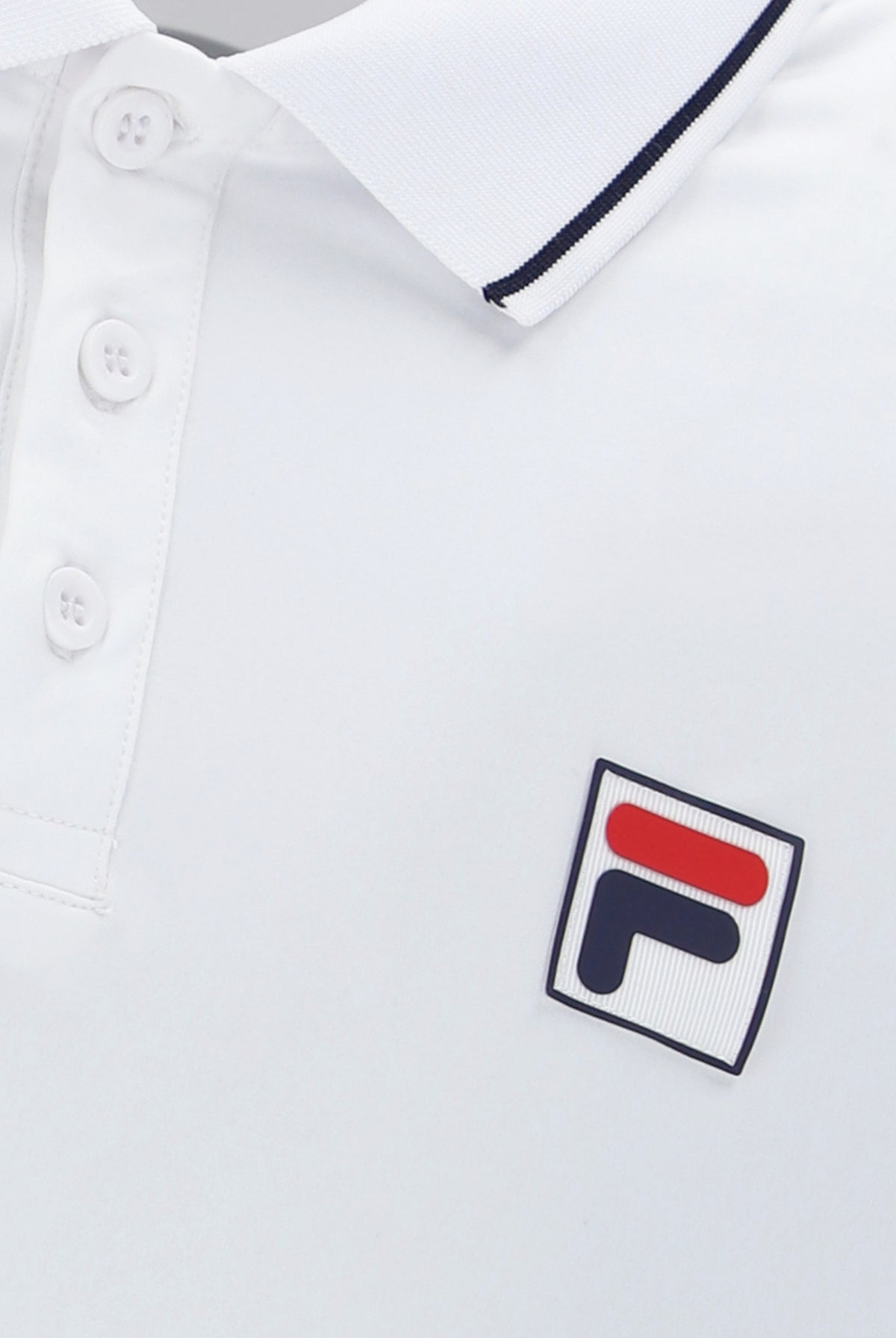 A white tennis polo shirt with button-up fastening and cap sleeve. It features the FILA logo and a small GB flag on the chest.