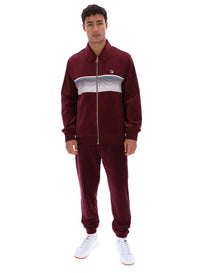 Man wearing a burgundy track top with a FILA logo, paired with matching bottoms, against a white background