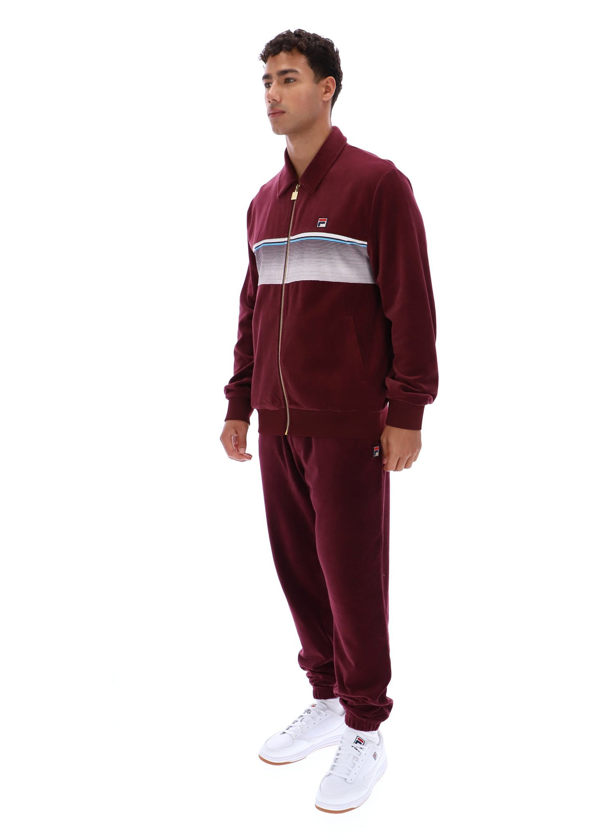 Man wearing a burgundy track top with a FILA logo, paired with matching bottoms, against a white background