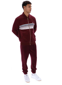 Man wearing a burgundy track top with a FILA logo, paired with matching bottoms, against a white background