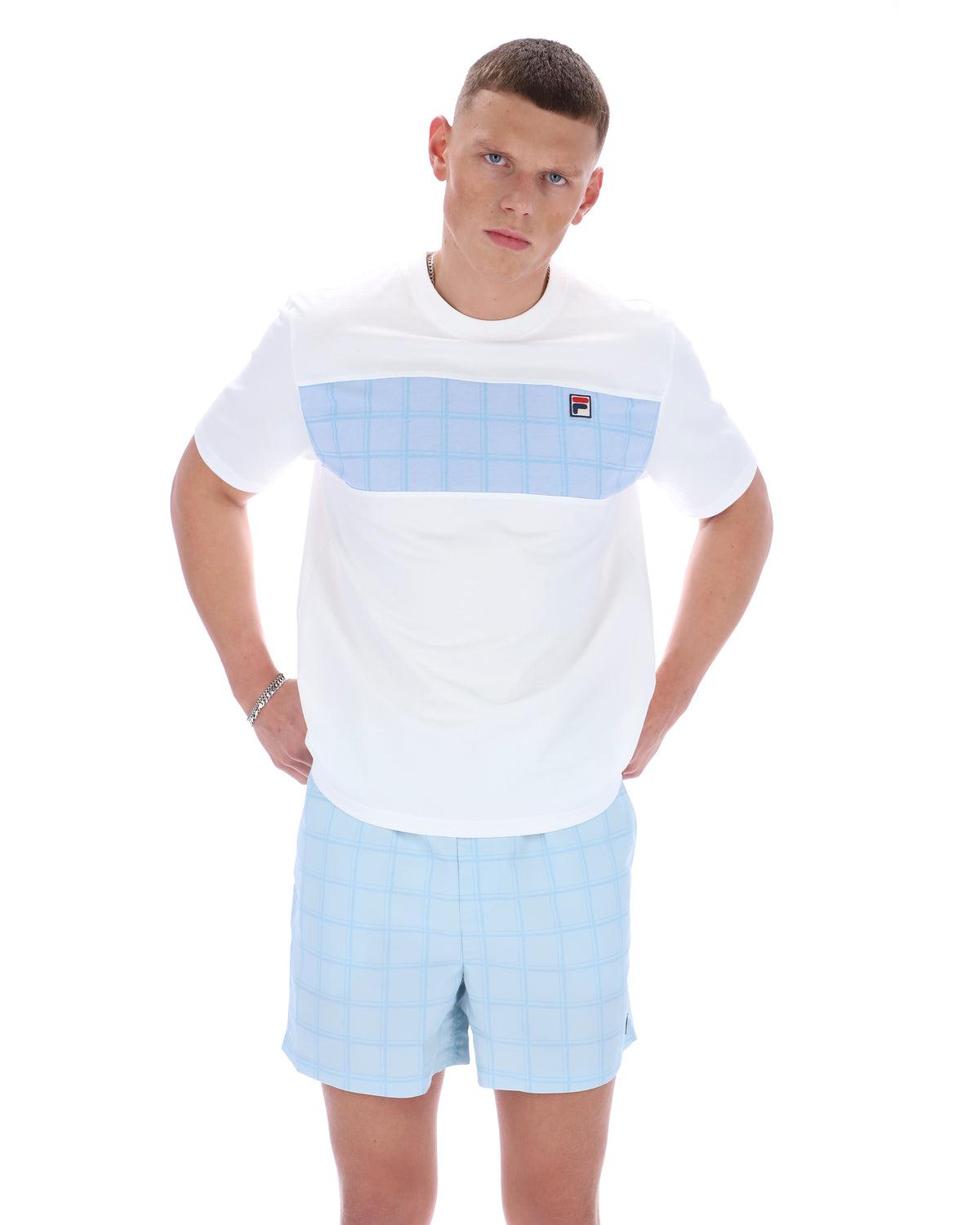 Man wearing a white t-shirt with a blue pocket and light blue shorts on a white background
